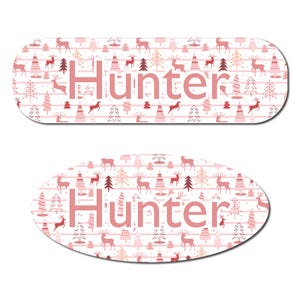 May include: Two decorative name tags with a pink and white pattern featuring deer and trees. The name "Hunter" is displayed in pink block letters on both tags. One tag is rectangular, and the other is oval.