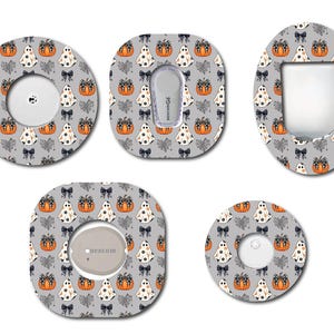 May include: A collection of Halloween-themed medical device covers in various shapes. The gray covers feature a repeating pattern of white ghosts, orange pumpkins, black bows, and leaves. Some covers have circular or oval cutouts.