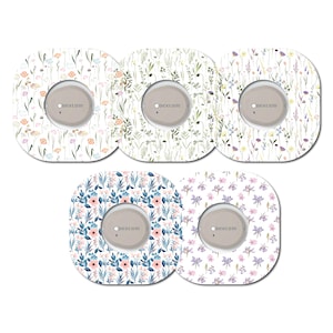 May include: Five different designs of round, white, adhesive stickers with a floral pattern. Each sticker has a small, round, grey area in the centre with the text "dexcom" printed on it.