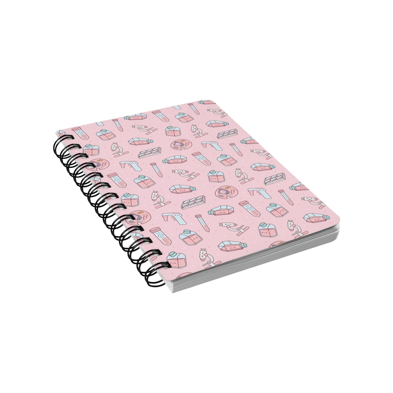 Peut inclure: Un carnet &agrave; spirales rose avec un motif d'illustrations sur le th&egrave;me des sciences, comprenant des b&eacute;chers, des tubes &agrave; essai, des microscopes et des bo&icirc;tes de P&eacute;tri.