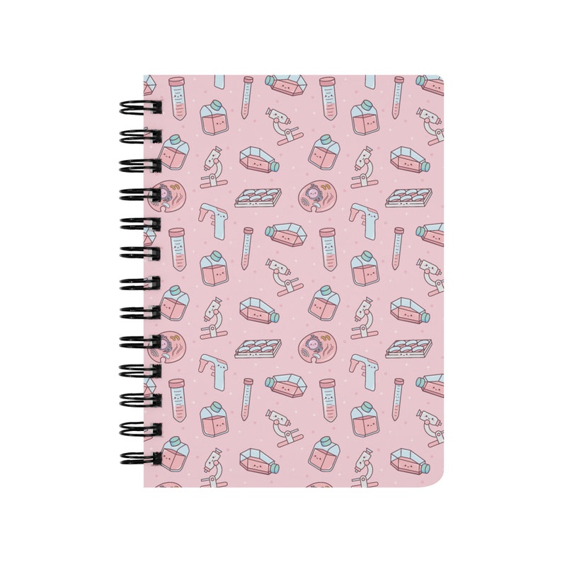 Peut inclure: Un carnet &agrave; spirales rose avec un motif d'illustrations sur le th&egrave;me des sciences. Les illustrations comprennent des b&eacute;chers, des tubes &agrave; essai, des microscopes et des bo&icirc;tes de P&eacute;tri. Les illustrations sont en rose, bleu et blanc.