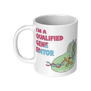Peut inclure: Une tasse en c&eacute;ramique blanche avec une illustration verte, bleue et rouge d'une cha&icirc;ne d'ADN coup&eacute;e par des ciseaux. Le texte "I'm a Qualified Gene Editor" est imprim&eacute; en rose et bleu sur la tasse. Le texte "CRISPR-Cas9" est imprim&eacute; en noir au bas de l'illustration.