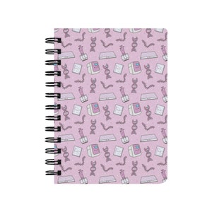 May include: A pink spiral bound notebook with a repeating pattern of science-themed illustrations. The illustrations include a DNA strand, a test tube, a petri dish, and a scientific instrument.