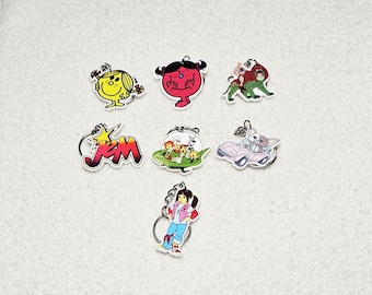 May include: A selection of seven cartoon character keyrings. The keyrings feature various colourful designs, including characters from the "Little Miss" series, a "Jem" logo, and other cartoon figures. Each keyring has a silver-coloured ring.