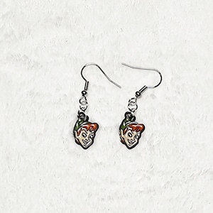 May include: A pair of dangle earrings featuring small, colorful enamel charms of a smiling character with red hair and a green hat. The charms are attached to silver-toned metal fishhook wires with small jump rings, creating a simple drop design.