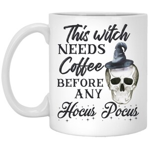 May include: White ceramic coffee mug with the text "This witch NEEDS Coffee BEFORE ANY Hocus Pocus" in black script. A skull wearing a witch hat is on the right side of the mug. The mug has a white handle.