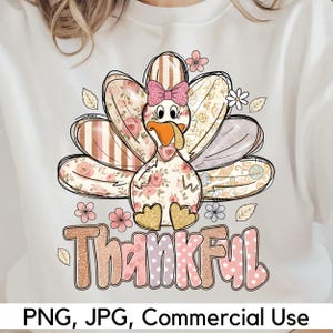 Könnte beinhalten: Weißes Sweatshirt mit einem Thanksgiving-Truthahn-Design. Der Truthahn hat ein Blumenmuster, eine rosa Schleife und das Wort "Thankful" in einer glitzernden Schriftart. Das Design enthält rosa und goldene Akzente, mit dem Text "PNG, JPG, Commercial Use" unten.