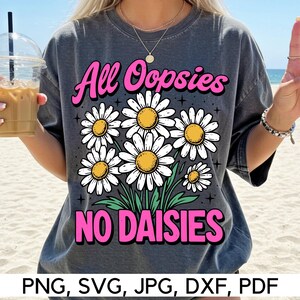 May include: Dark gray t-shirt with the text "All Oopsies NO DAISIES" in pink, with a daisy flower graphic. The shirt has a crew neck and short sleeves. The bottom of the image shows the file types: PNG, SVG, JPG, DXF, PDF.