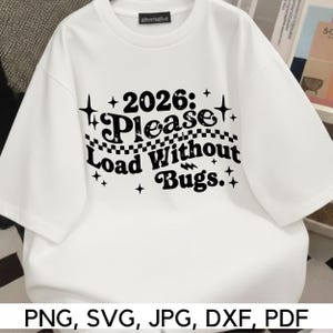 May include: White t-shirt with the text "2026: Please Load Without Bugs" in black. The shirt has a crew neck and short sleeves. The brand name "alternative" is printed on the collar.