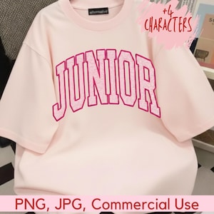 Peut inclure: Un t-shirt rose clair avec le mot "JUNIOR" en rose vif, dans une police de style universitaire sur le devant. Le t-shirt a des manches courtes et un col rond. La marque "alternative" est imprimée sur le col.