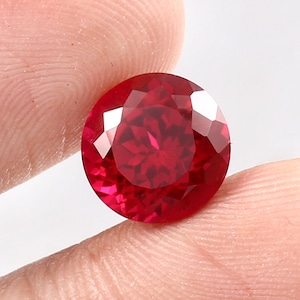 Peut inclure: Une pierre précieuse rouge foncé de forme ronde et à facettes.