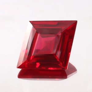May include: A deep red gemstone with a square shape and a faceted cut.