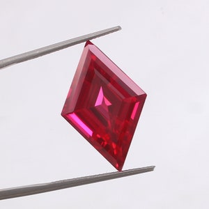 May include: A bright red, faceted, square-shaped gemstone with a diamond-like cut.