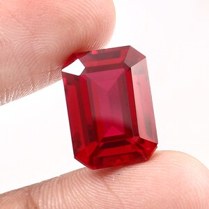 May include: A deep red emerald cut gemstone with a high polish.