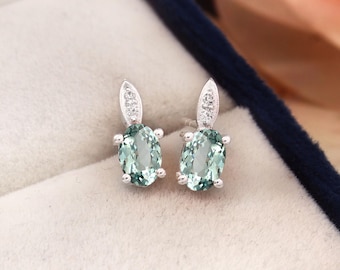 Peut inclure: Une paire de boucles d'oreilles en argent avec une pierre ovale vert clair et un petit accent diamant sur chaque boucle d'oreille.