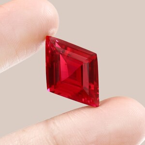 Può includere: Una pietra preziosa di colore rosso intenso con taglio quadrato e forma di diamante.