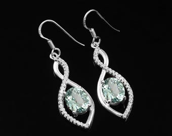 Peut inclure: Boucles d'oreilles pendantes en argent avec une pierre ovale bleu clair sertie dans un motif infini en argent.