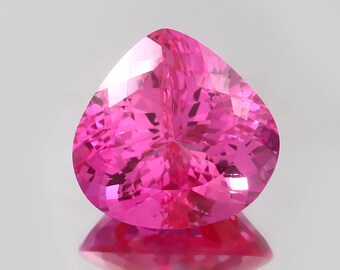 May include: A vibrant pink pear-shaped gemstone with a faceted cut. The gem is set against a white background.