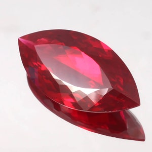 Può includere: Una pietra preziosa di forma marquise di colore rosso intenso con taglio a faccette.