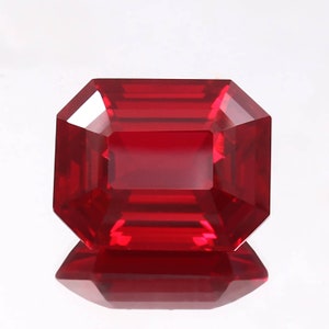 May include: A deep red emerald cut gemstone with a high polish.