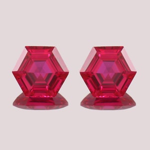 May include: Two bright red hexagonal gemstones with a faceted design.