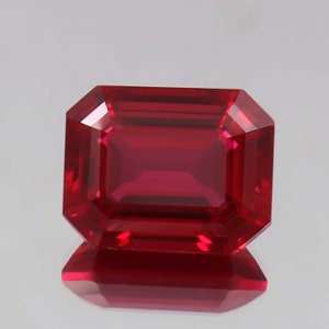 May include: A deep red emerald cut gemstone with a high polish.