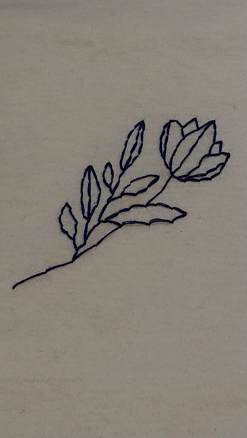 Puede incluir: Dise&ntilde;o de bordado floral cosido a mano con una flor y hojas azul oscuro sobre una tela beige claro. El bordado muestra un contorno delicado de una flor y follaje, creando una est&eacute;tica simple pero elegante.
