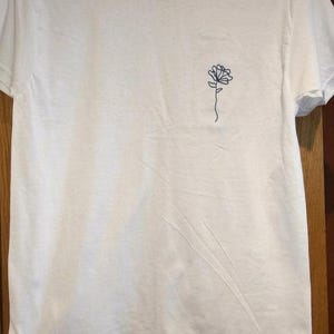 Camiseta unisex de algodón con bordado floral, diseño minimalista de líneas botánicas, color de hilo personalizado. imagen 1