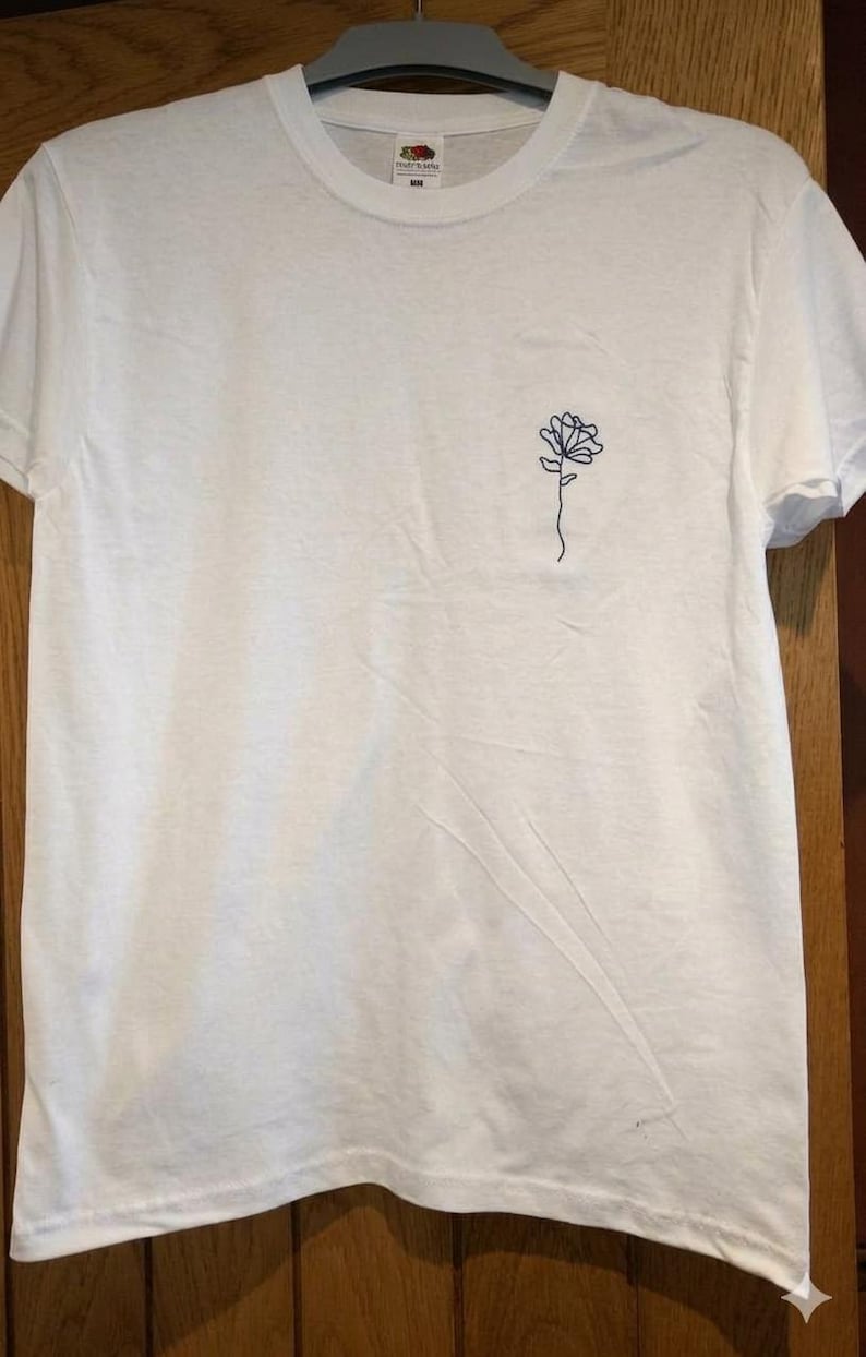 Camiseta unisex de algodón con bordado floral, diseño minimalista de líneas botánicas, color de hilo personalizado. imagen 1