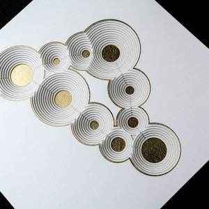 Op de afbeelding: Wit papier met een gouden ontwerp van overlappende cirkels. De cirkels zijn gelaagd om een 3D-effect te cre&euml;ren.