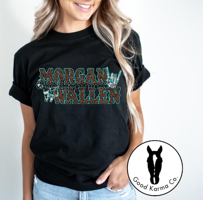 Peut inclure: T-shirt noir avec un motif brun et turquoise qui dit "Morgan Wallen" avec un graphique de geste de la main. Le design est de Good Karma Co.