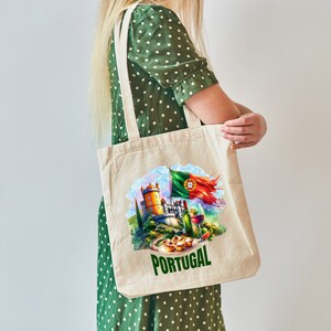 Puede incluir: Una bolsa de tela blanca con una ilustraci&oacute;n colorida de un castillo portugu&eacute;s, una bandera, vino y pasteles. El texto "PORTUGAL" est&aacute; impreso en verde debajo de la ilustraci&oacute;n.