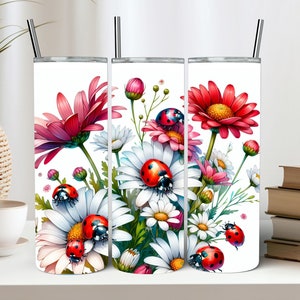 May include: Three stainless steel tumblers with a white background and a floral design featuring pink and white flowers, green leaves, and red ladybirds.