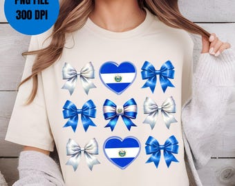 May include: A white t-shirt with a blue and white heart-shaped design featuring the flag of El Salvador. The heart is surrounded by eight blue and white bows.