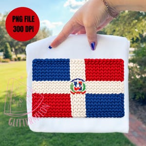 Op de afbeelding: Een wit stoffen item met een gebreid ontwerp van de vlag van de Dominicaanse Republiek. Het vlagontwerp bevat blauwe, rode en witte secties met een centraal embleem. De tekst "PNG FILE 300 DPI" is ook inbegrepen.