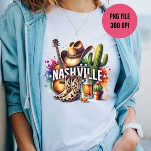 Pu&ograve; includere: Una maglietta bianca con un design colorato che presenta un cappello da cowboy, stivali, una chitarra, cactus e la parola "Nashville".