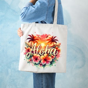 May include: A white tote bag with a colorful design featuring palm trees, a sunset, and the word "Aloha" in a stylized font. The design is surrounded by pink, orange, and yellow hibiscus flowers.