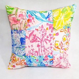 Puede incluir: Una funda de coj&iacute;n de patchwork con fondo blanco y coloridos patrones florales y tropicales. La funda de coj&iacute;n est&aacute; hecha de diferentes telas cosidas juntas en un patr&oacute;n de cuadr&iacute;cula.