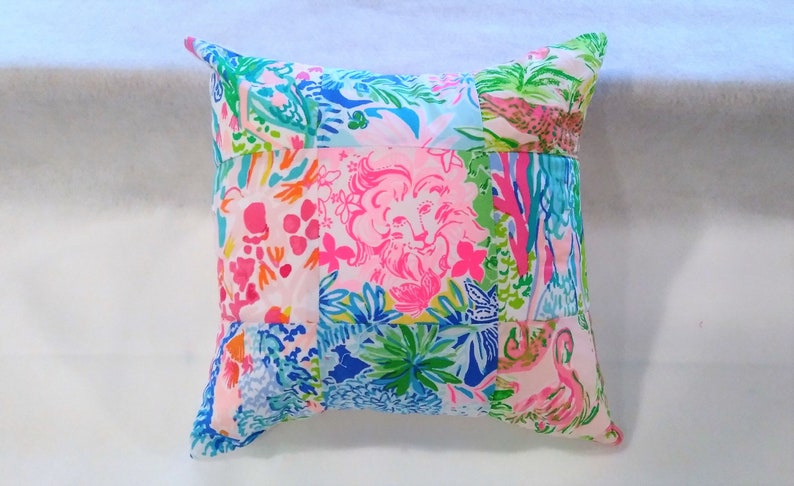 Puede incluir: Una almohada de patchwork con un estampado floral rosa, azul y verde. La almohada est&aacute; hecha de diferentes telas y tiene una forma cuadrada.