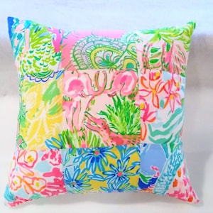 May include: A patchwork pillow cover with a variety of floral and animal prints in pink, green, blue, and yellow.