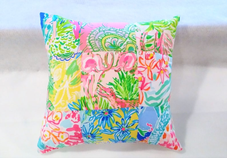 Puede incluir: Una funda de coj&iacute;n de patchwork con una variedad de estampados florales y animales en rosa, verde, azul y amarillo.