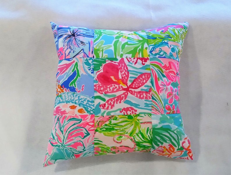 Puede incluir: Una almohada de patchwork con un dise&ntilde;o floral en tonos de rosa, azul y verde. La almohada est&aacute; hecha de diferentes telas con varios patrones florales.