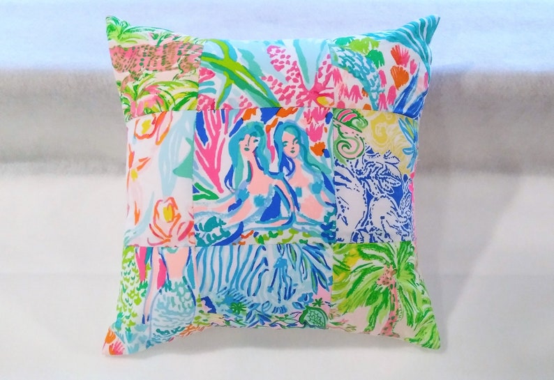 Puede incluir: Una funda de coj&iacute;n de patchwork con un dise&ntilde;o colorido que presenta sirenas, palmeras y otros motivos tropicales.