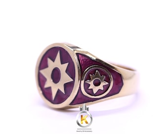 May include: A gold ring with a red enamel design featuring two eight-pointed stars. The ring is a statement piece with a bold and unique design.