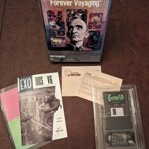 Op de afbeelding: Een boxed eXoDOS 6 Forever Voyaging-gameset met een portret van een man op de doos. Inclusief een gebruikershandleiding, een diskette en andere inzetstukken. De doos en handleiding hebben de tekst "eXoDOS 6" en "Forever Voyaging".