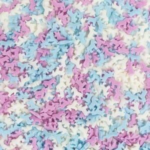 Könnte beinhalten: Nahaufnahme von pastellblauen, rosa und weißen Streuseln in Form von kleinen Pferden. Die Streusel eignen sich perfekt zum Dekorieren von Kuchen, Cupcakes und anderen Desserts.