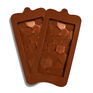 Può includere: Due stampi in silicone marrone con un motivo a nido d'ape. Ogni stampo ha una forma rettangolare con la parte superiore arrotondata e un piccolo foro per appenderlo. Gli stampi sono progettati per realizzare cioccolatini, saponi o altri oggetti artigianali.