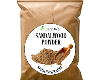 May include: A brown paper bag with a white label that says "100% Organic Sandalwood Powder Santalum Spicatum". The label has a green leaf design and a wooden scoop is partially visible in the bag.