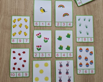 May include: A set of 10 colorful flashcards with various images and numbers. The images include a bird, a rainbow, grass, flowers, boots, eggs, a sun, and bunnies. Each card has a number from 1 to 10.