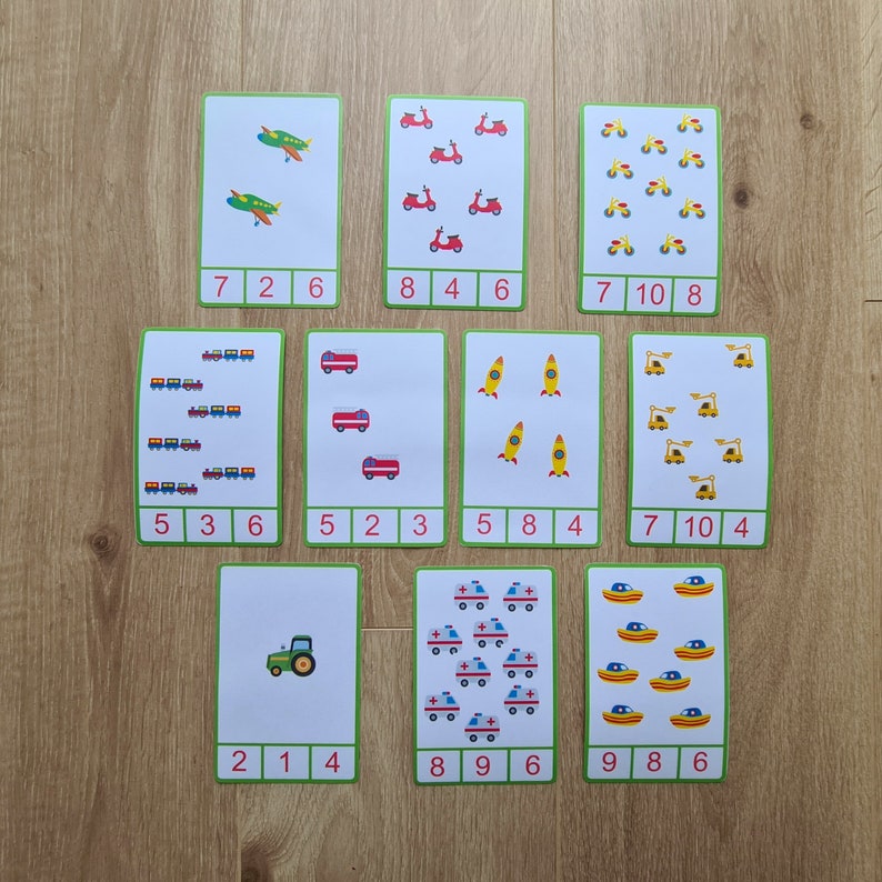 May include: Nine flashcards with colorful illustrations of different vehicles, including airplanes, scooters, tractors, fire trucks, rockets, cranes, ambulances, boats, and trains. Each card has a number and a quantity of the illustrated vehicle.